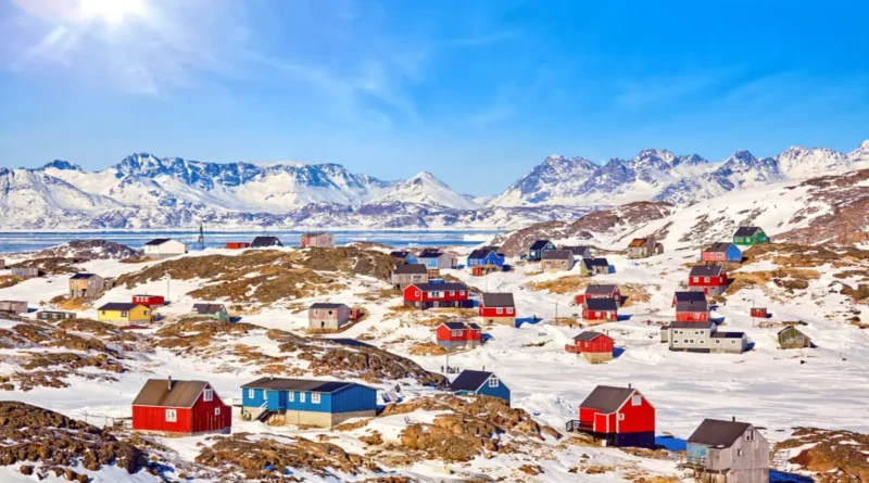 Colorful houses in a snow-covered town in Greenland with mountains in the background