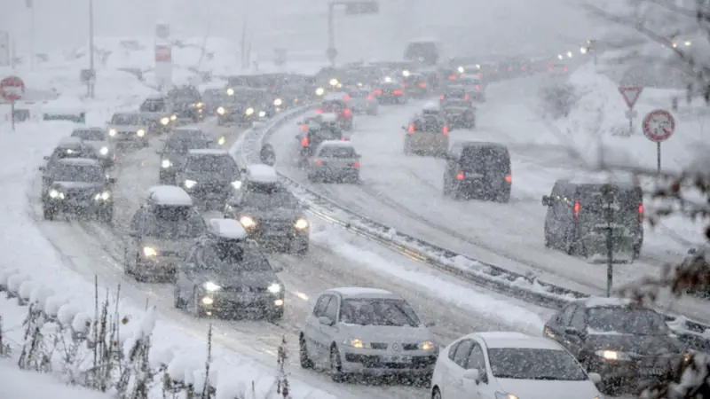 Cars moving slowly on a snow-covered road during a winter storm