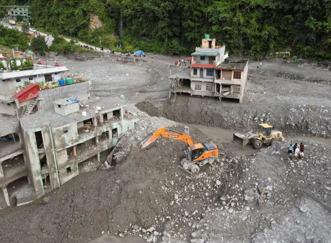 Rescue workers and excavators clear debris from flood-damaged buildings in Nepal